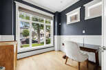 This home office features a large picture window offering views of the neighborhood and mature trees.