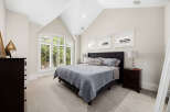 Experience luxury in this master bedroom, featuring a grand arched window with plantation shutters that flood the space with natural light.