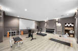 Elevate your fitness routine in this well-appointed home gym, featuring a Peloton bike, treadmill, and a complete weight set with a bench.