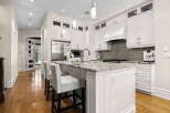 Experience luxury in this stunning kitchen featuring sleek white cabinetry, a spacious granite island with bar seating, and high-end stainless steel appliances.