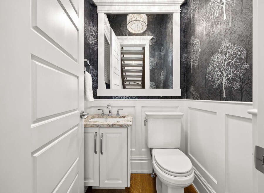 This powder room features a stylish vanity with a granite countertop and a white toilet.