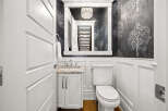 This powder room features a stylish vanity with a granite countertop and a white toilet.