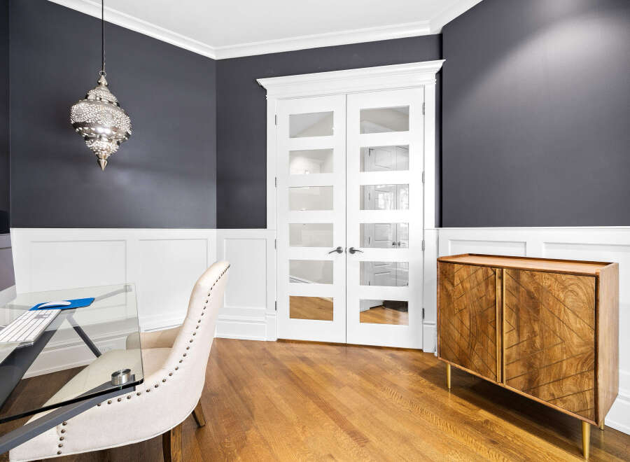 This elegant home office features a sophisticated dark gray and white color palette, complemented by a stunning Moroccan-inspired pendant light.