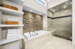 Experience luxury in this stunning bathroom featuring a deep soaking tub set against a captivating stacked stone accent wall.
