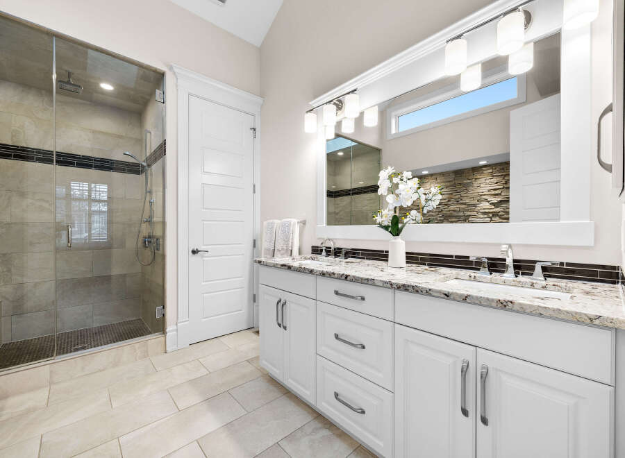 Experience luxury in this stunning bathroom featuring a spacious glass-enclosed shower with elegant tilework and a sleek dual vanity.