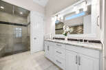 Experience luxury in this stunning bathroom featuring a spacious glass-enclosed shower with elegant tilework and a sleek dual vanity.