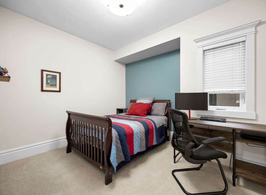 This charming bedroom features a comfortable bed with a colorful striped quilt, perfect for a cozy retreat.