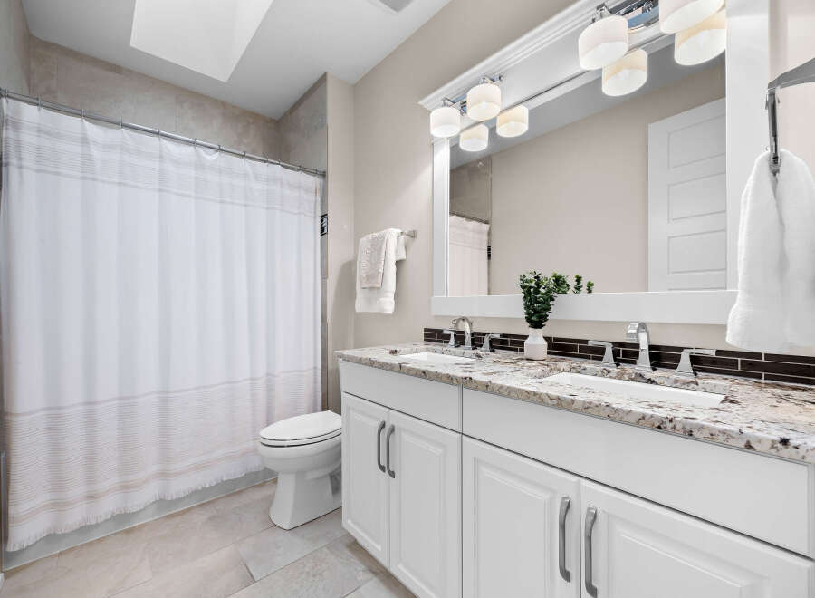 This modern bathroom features a spacious double vanity with a granite countertop and sleek chrome fixtures, perfect for busy mornings.