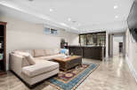 This finished basement offers a stylish entertainment space with a large sectional sofa, a rustic wooden coffee table, and a built-in bar with glass-front cabinets perfect for showcasing beverages.