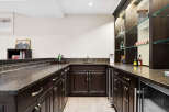 This elegant home bar features dark wood cabinetry with brushed nickel hardware, complemented by a speckled granite countertop.