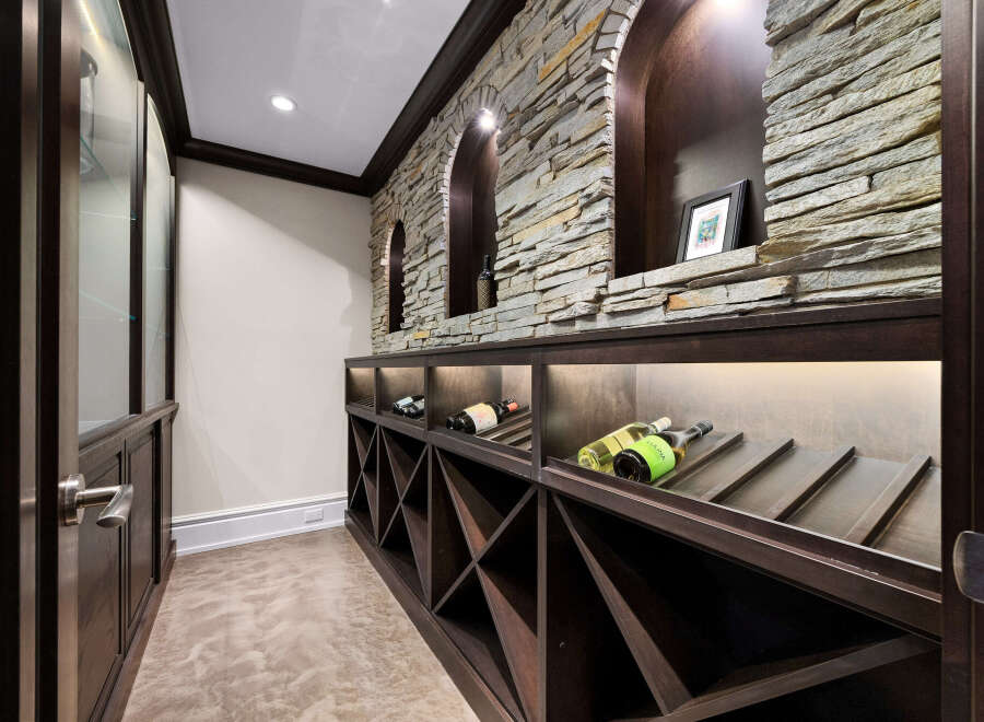 Discover this exquisite wine cellar, featuring a stunning stacked stone accent wall with arched niches, perfect for displaying your finest vintages.