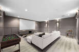 Experience ultimate entertainment in this sophisticated basement media room, featuring a large projection screen and comfortable sectional sofa.