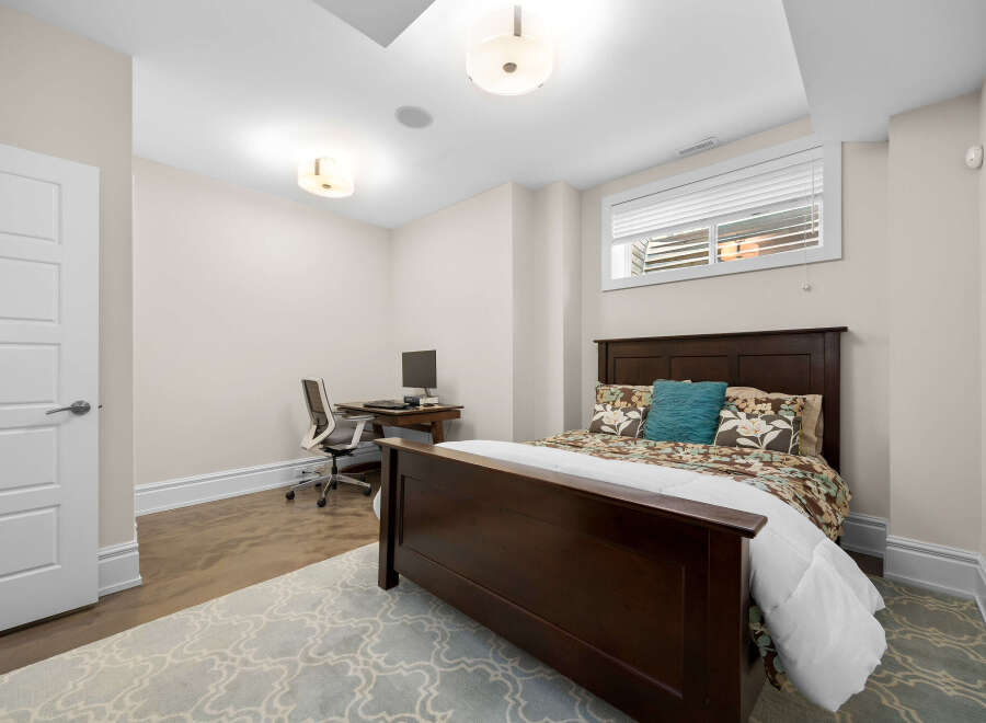 This inviting bedroom features a comfortable queen-size bed with a dark wood headboard, adorned with floral print bedding and a decorative teal pillow.