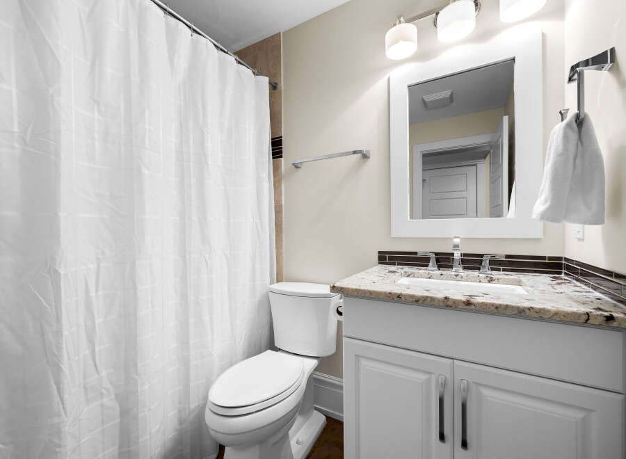 This bathroom features a white toilet and a vanity with a granite countertop and a modern faucet.