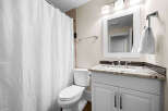 This bathroom features a white toilet and a vanity with a granite countertop and a modern faucet.