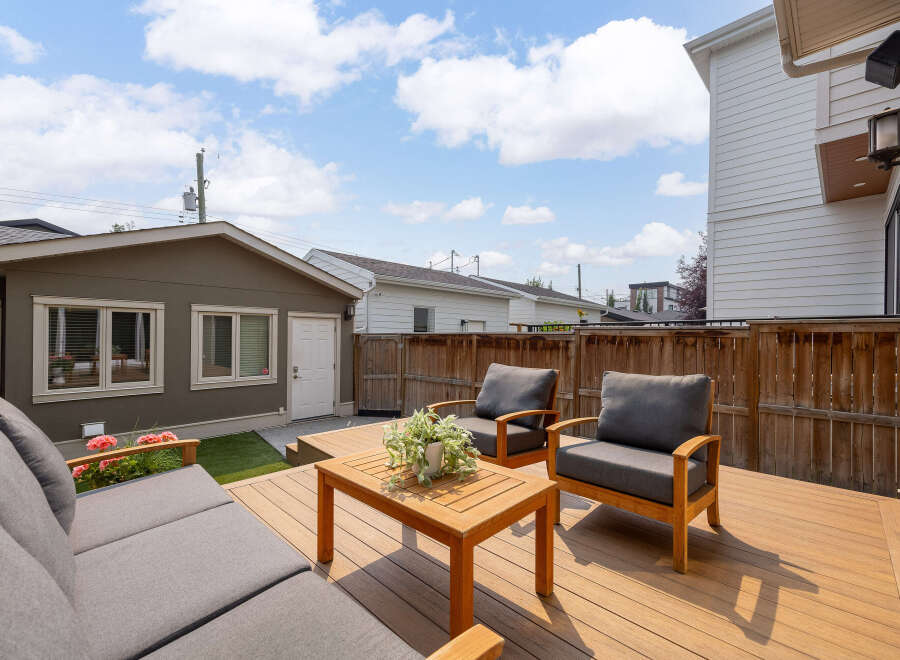 Enjoy outdoor living in this spacious backyard featuring a large wooden deck perfect for entertaining.