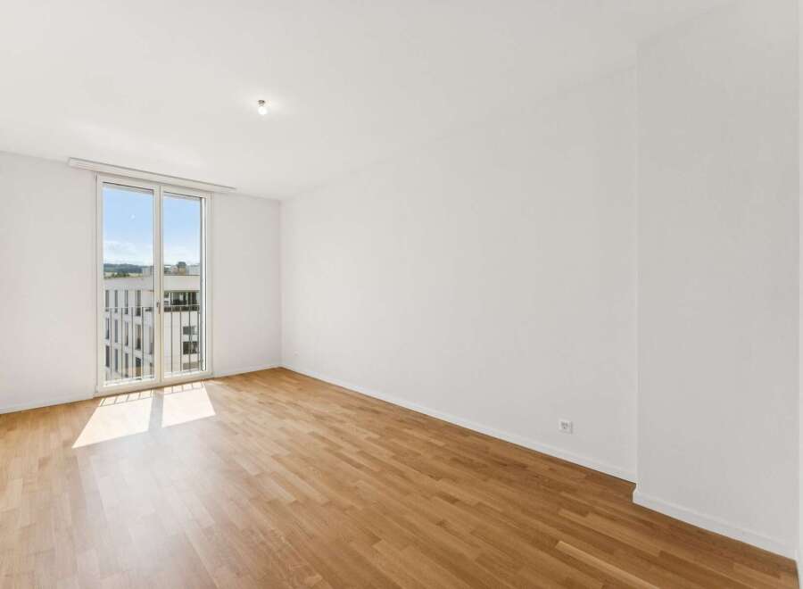 Experience modern living in this bright and airy unfurnished apartment, featuring a spacious living area with abundant natural light streaming through large glass doors.
