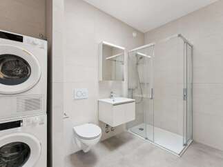 This modern bathroom features a stacked washer and dryer unit, a wall-mounted toilet with a dual-flush system, and a sleek vanity with a sink.