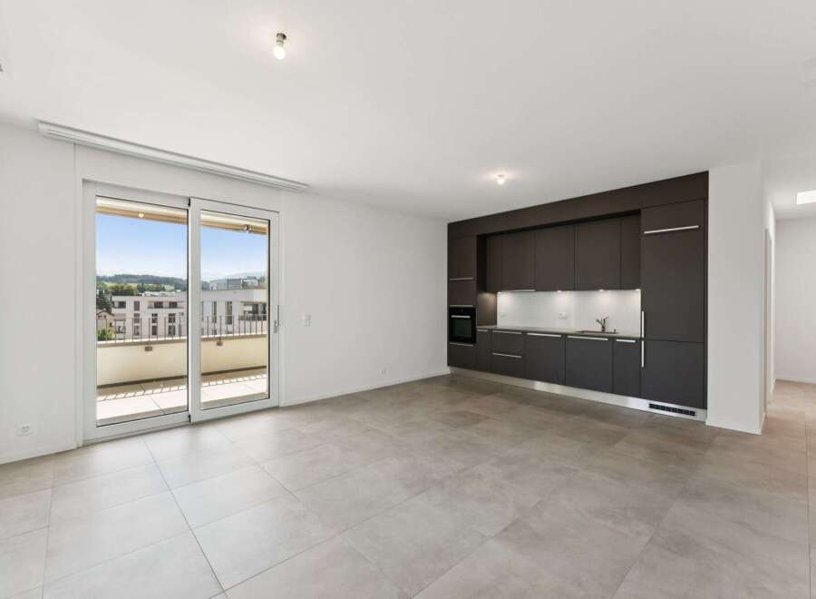 Experience modern living in this spacious apartment featuring a sleek, dark-toned kitchen with integrated appliances and ample cabinet space.