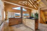 Experience luxurious mountain living in this stunning wooden chalet featuring a modern kitchen with a sleek black countertop and a striking black faucet.