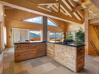 Experience luxurious mountain living in this stunning wooden chalet featuring a modern kitchen with a sleek black countertop and a striking black faucet.