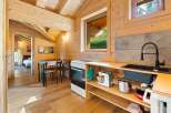 Experience cozy living in this charming wooden cabin, featuring a well-equipped kitchen with modern appliances and a dining area perfect for intimate meals.