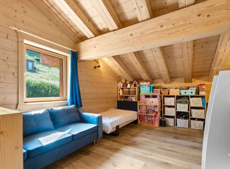 Discover this charming attic bedroom, perfect for children, featuring a cozy blue sofa and a twin bed.