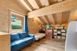 Discover this charming attic bedroom, perfect for children, featuring a cozy blue sofa and a twin bed.
