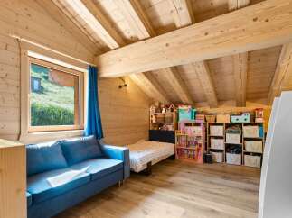 Discover this charming attic bedroom, perfect for children, featuring a cozy blue sofa and a twin bed.