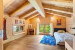 Experience serene living in this charming wooden cabin bedroom, featuring a vaulted ceiling with exposed beams and natural wood finishes throughout.