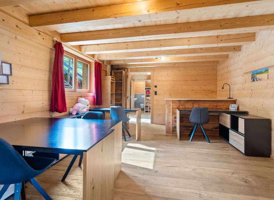 Experience rustic charm in this beautifully appointed wooden cabin, featuring a spacious dining area with dark tabletops and comfortable seating.