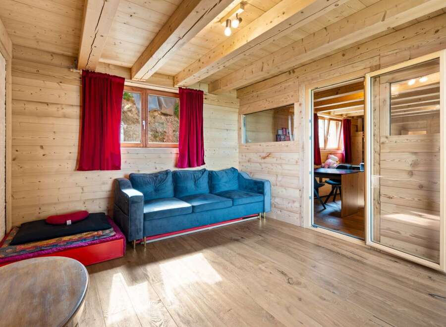 Experience rustic charm in this cozy wooden cabin, featuring a plush blue sofa perfect for relaxation.