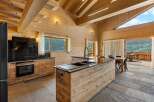 Experience luxurious mountain living in this stunning wooden chalet kitchen, featuring a sleek black granite countertop and a large island with a modern faucet.