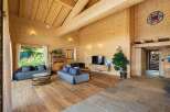 Experience rustic luxury in this stunning wooden chalet living room, featuring exposed beams, a vaulted ceiling, and a cozy fireplace area.