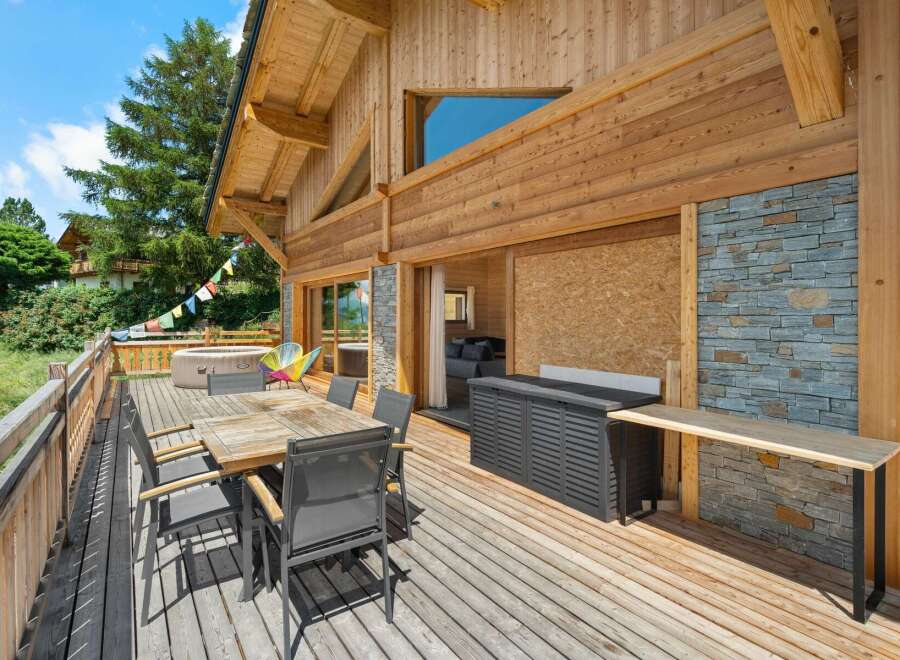 Enjoy outdoor living on this spacious wooden deck, complete with a dining set and a relaxing hot tub.
