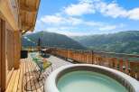 Experience breathtaking mountain views from this stunning chalet deck, complete with a relaxing hot tub and comfortable seating area.