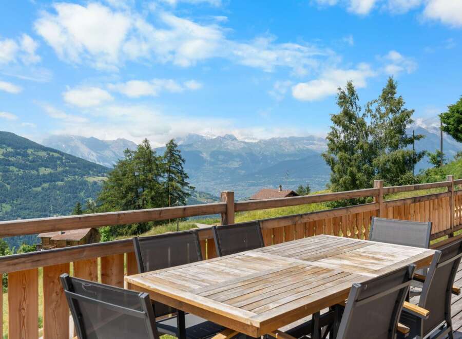 Enjoy breathtaking mountain views from this stunning property's expansive wooden deck, perfect for al fresco dining or simply soaking in the scenery.