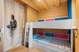 This charming wooden cabin bedroom features a white bunk bed with colorful accents, perfect for a family or guests.