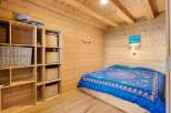 Experience cozy living in this charming wooden cabin bedroom, featuring a comfortable bed adorned with a vibrant blue and pink patterned duvet.
