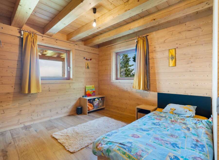 Experience cozy living in this charming wooden cabin bedroom, featuring a comfortable bed with playful Tarzan-themed bedding and a Simba pillow.
