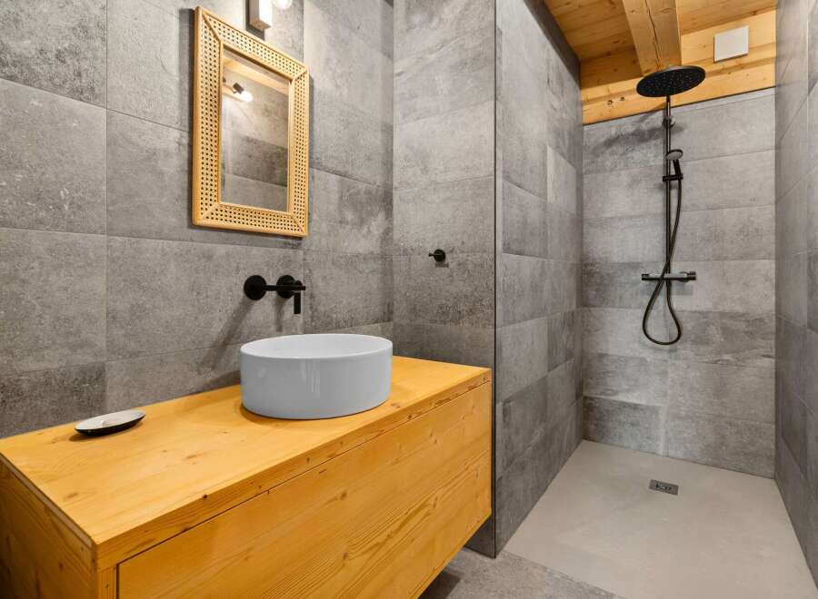 Experience modern luxury in this stunning bathroom featuring a sleek vessel sink atop a warm, wooden vanity.