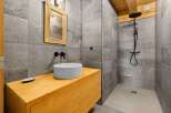 Experience modern luxury in this stunning bathroom featuring a sleek vessel sink atop a warm, wooden vanity.