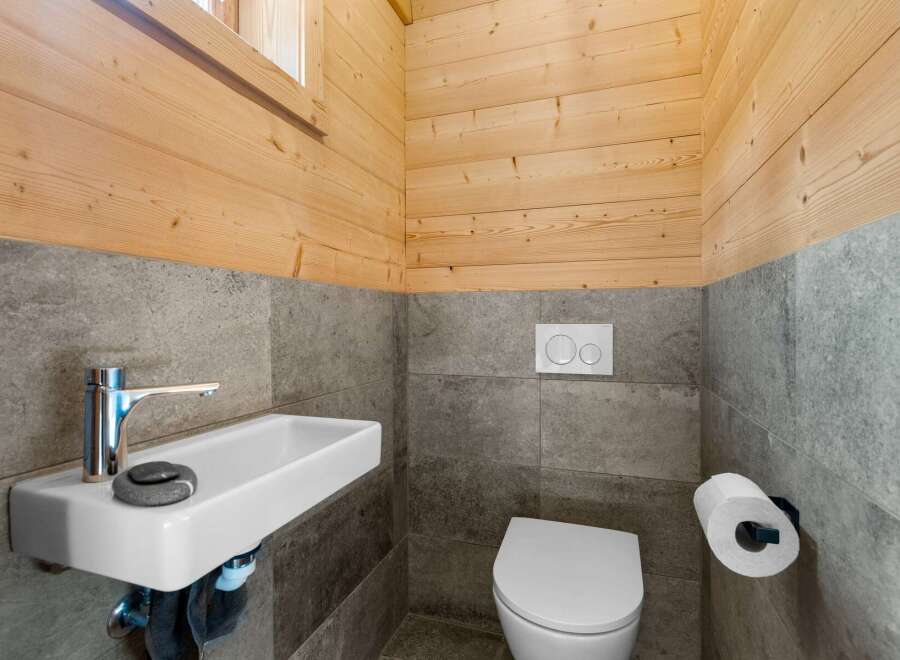 Experience modern comfort in this stylish bathroom featuring a sleek wall-mounted sink and a contemporary toilet with a dual-flush system.