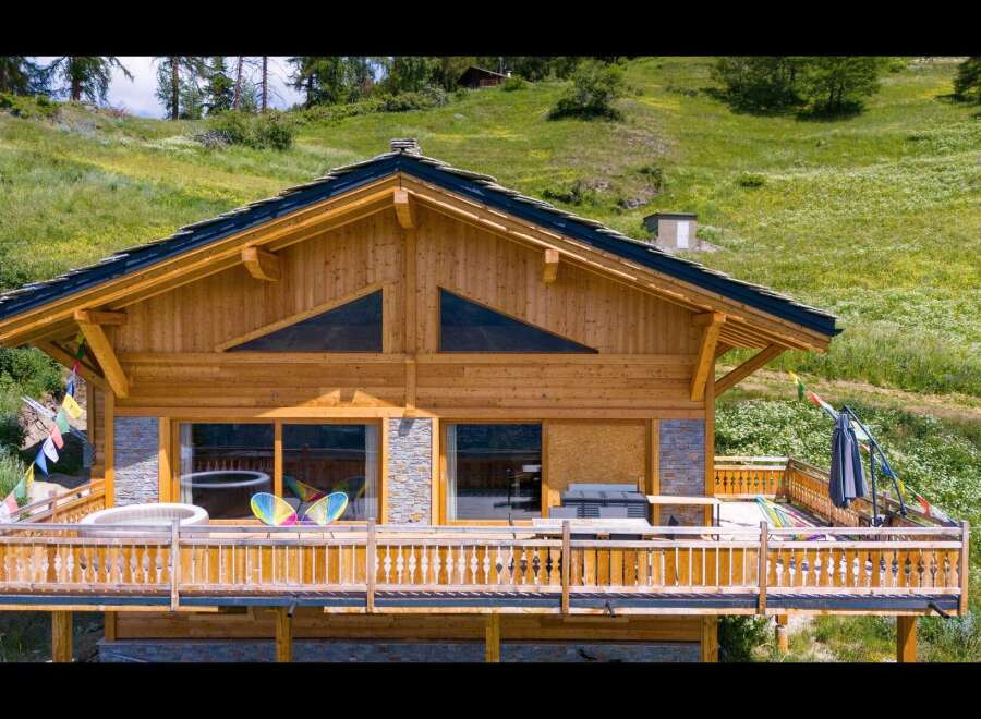 Experience luxury mountain living in this stunning wooden chalet, featuring a spacious deck with a hot tub and breathtaking panoramic views.