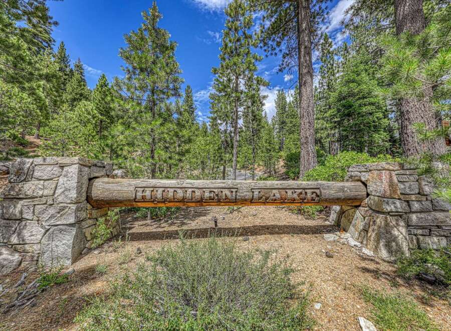 Discover the exclusive 'Hidden Lake' community, marked by this rustic log and stone entrance.