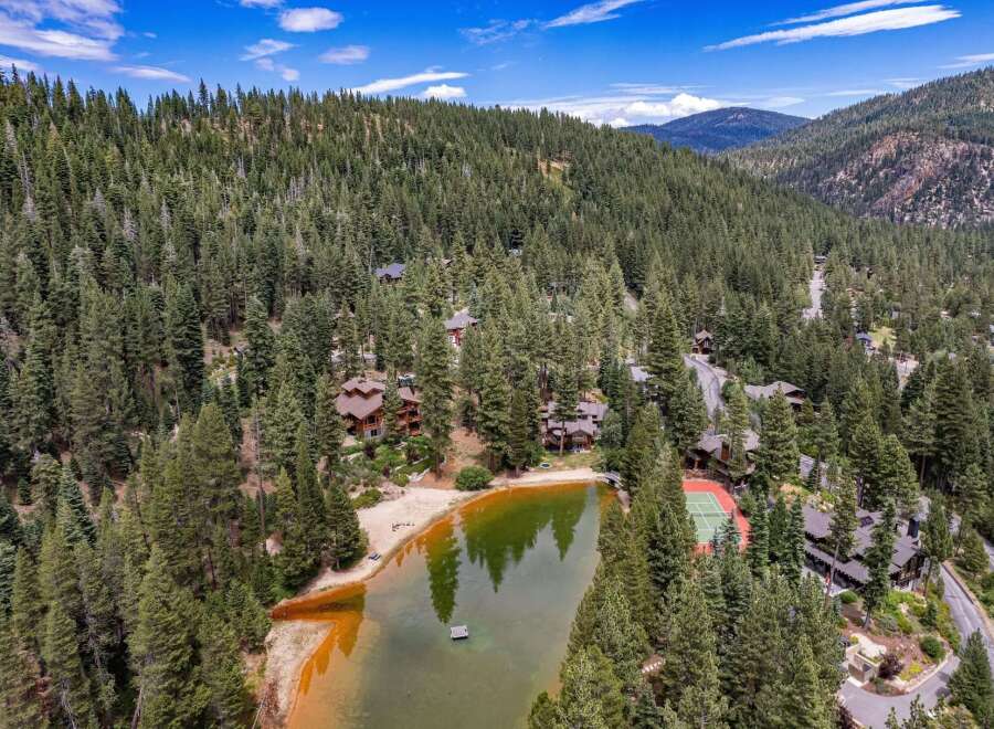 Nestled amidst a dense pine forest, this stunning property boasts a private lake with a sandy beach and a floating dock, perfect for serene relaxation.
