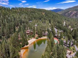 Nestled amidst a dense pine forest, this stunning property boasts a private lake with a sandy beach and a floating dock, perfect for serene relaxation.