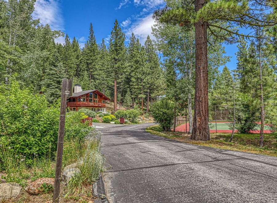 Nestled amidst towering pine trees, this stunning property offers a private oasis with a beautiful wooden home and a dedicated tennis court.