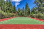 Enjoy outdoor recreation at this stunning property featuring a private tennis court surrounded by lush pine trees.