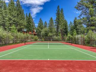 Enjoy outdoor recreation at this stunning property featuring a private tennis court surrounded by lush pine trees.